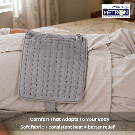 Woman using heating pad for period cramps stomach discomfort and back pain relief with gentle heat therapy at home by Metron