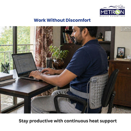 Man working comfortably on laptop using heating pad for continuous back support and pain relief during office work by Metron